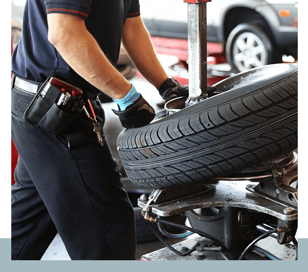 A person working on a tire in front of some cars.